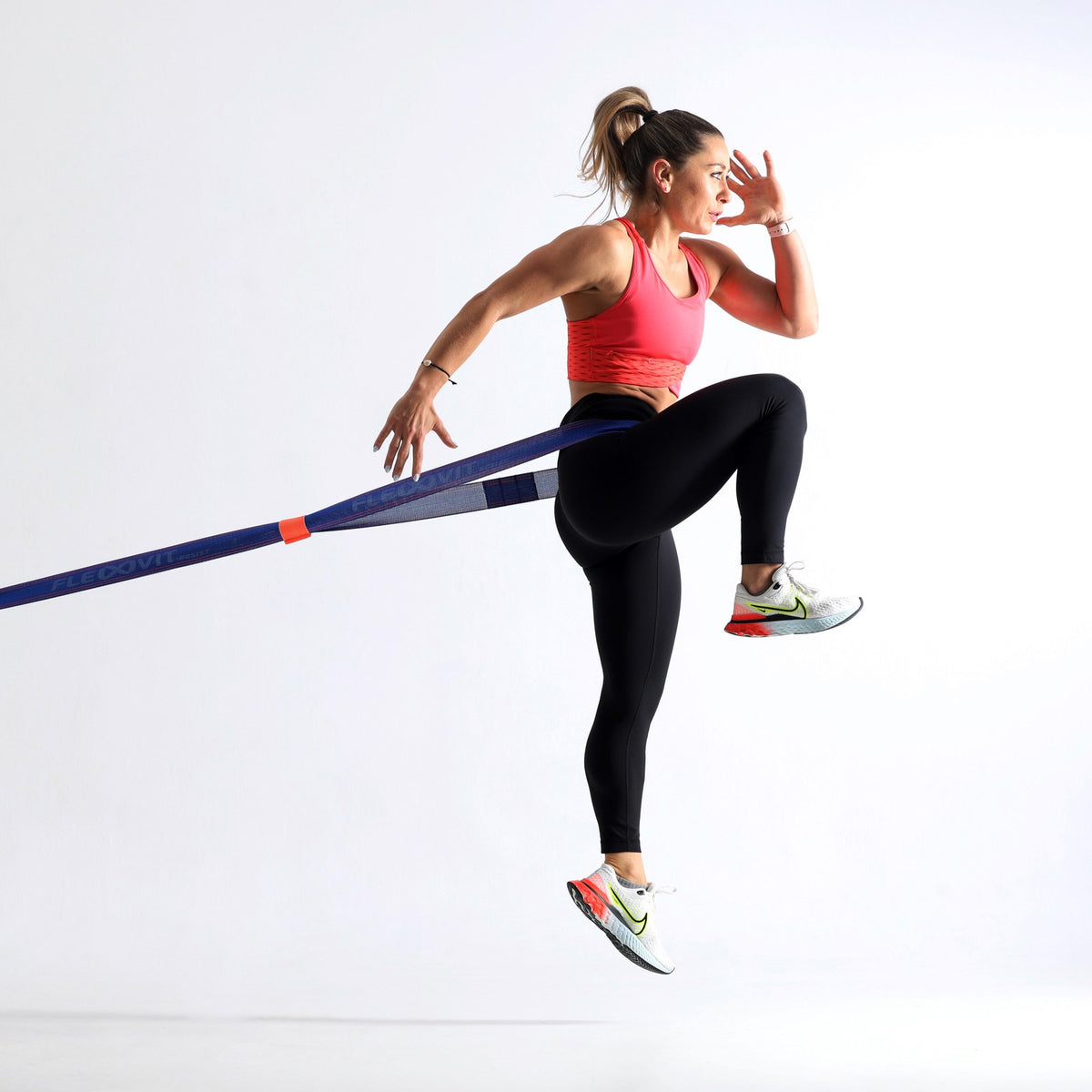 Mujer eleva una rodilla con la banda Flexvit Resist en la cintura, anclada a un costado