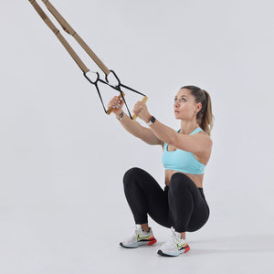 Mujer en sentadilla profunda sujetando las manijas de la banda Flexvit Sling