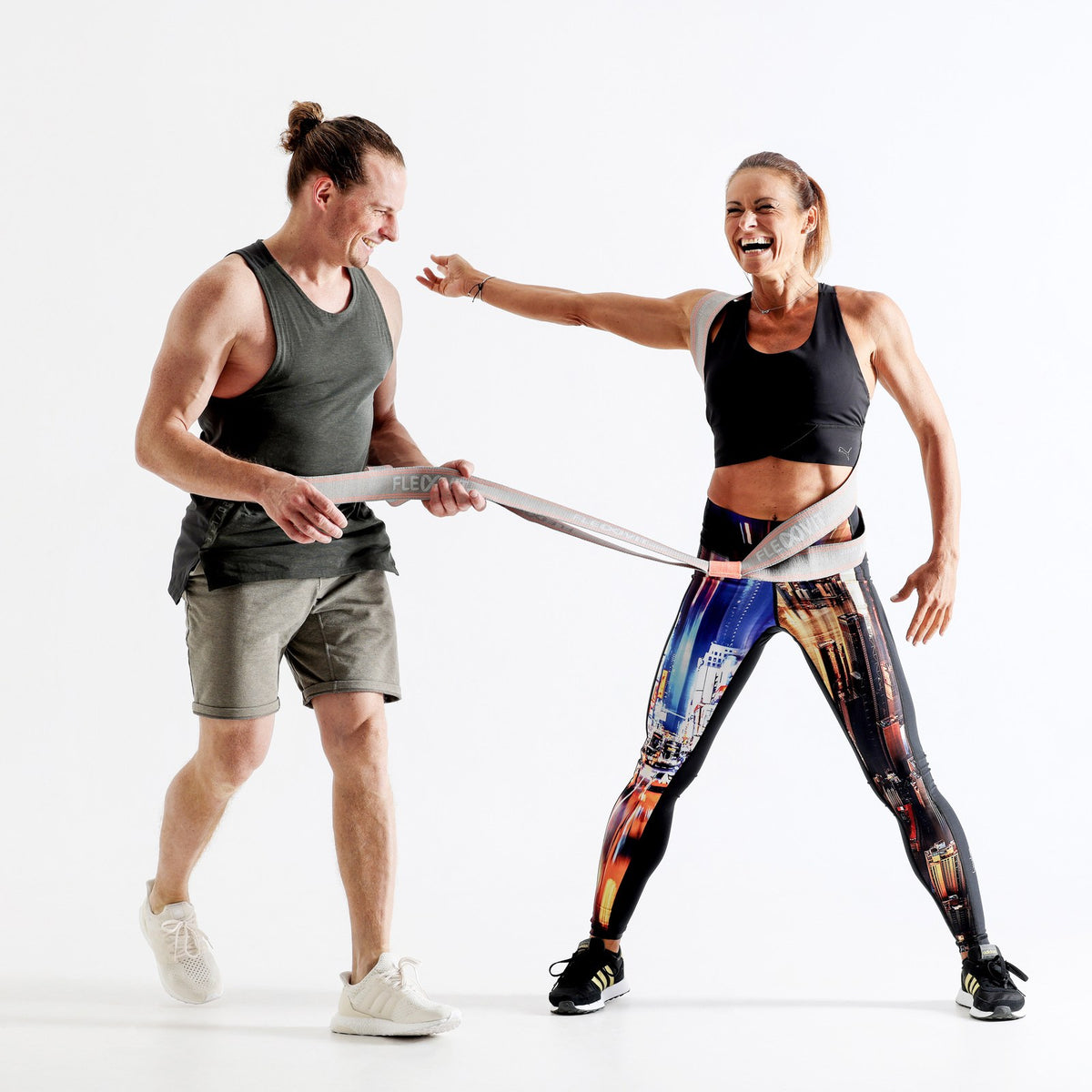 Hombre sostiene los extremos de una banda gris que rodea la cintura de una mujer, Flexvit Trainer Set